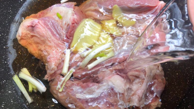 卤牛肉,浸泡好的牛腱冲洗干净放入锅里,放入一半的姜片和一半的葱段,倒入10克料酒,加入清水,水量和牛肉齐平,大火把水烧开,再煮2分钟关火,把牛腱用冷水冲洗干净待用。
