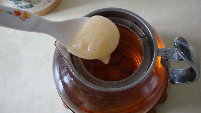青柠绿茶冰饮,取出茶叶滤网,把茶叶倒掉不用。茶水中放入蜂蜜搅至融化