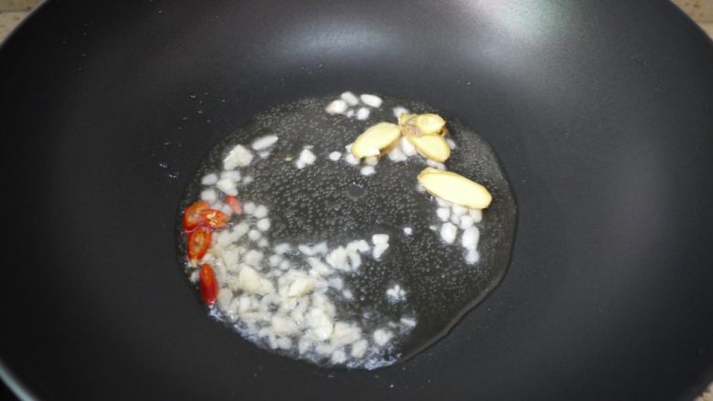 酱爆鱿鱼,另起油锅,油加热后加入蒜泥、姜片和辣椒爆香。