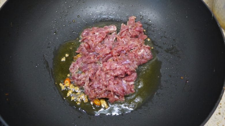 大葱炒牛肉,锅烧热加入适量的橄榄油,然后把大蒜、辣椒放入锅中爆香。然后倒入腌制好的牛肉。