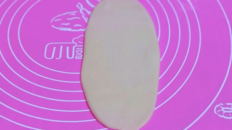 椰香桂花豆沙酥,取一面团,用掌心轻轻按压,再用擀面杖来回擀长舌状。