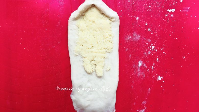 椰蓉面包(波兰种),把一头的面团按压薄,这样有利于收口,然后取出椰蓉,把椰蓉平铺在面团上
