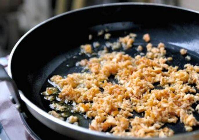 鮭鱼炒饭 ,锅内重新倒入 1 匙油,转中火继续将鮭鱼炒至乾鬆,让部分的鱼肉带焦可增加香气,接著以胡椒和盐调味后,再倒入葱白和洋葱拌炒