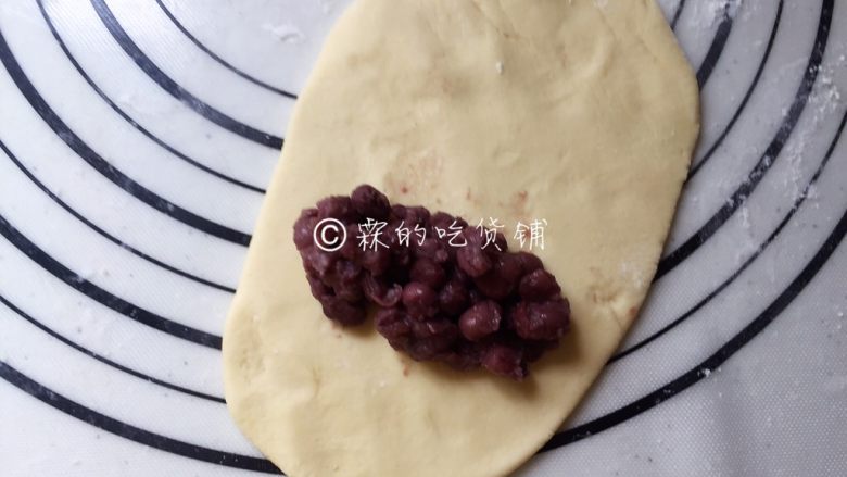 玉米面蜜红豆发面饼,把剂子擀成长面片状,在底部位置放上<a style='color:red;display:inline-block;' href='/shicai/ 8019'>蜜红豆</a>。