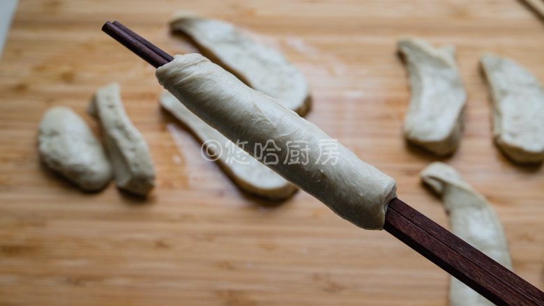 烤面筋,用一双筷子先夹住面筋的一头,一手拉伸拉长面团,一手转动筷子,让面团斜着缠绕在筷子上,最后的面团要抻开抻薄包裹住筷子上的面团,最后就是图中的样子。面团最后不抻薄也可以,直接缠绕就行。
