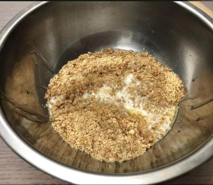 百香芒果双层生乳酪蛋糕(免烤箱),加入融化的无盐奶油,以橡皮刮刀或汤匙将饼乾碎和奶油混合均匀。