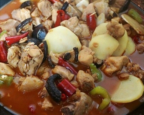 黄焖鸡米饭,时间到后开盖,放入土豆片和青椒,改大火继续煮,煮到汤汁快收完时,土豆也就熟了