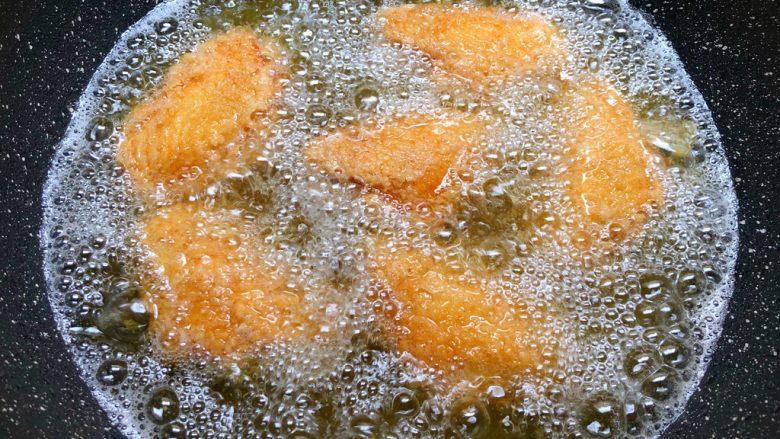 香酥鸡翅,热锅放入500毫升油,烧至7成热,把鸡翅一个个放到油锅里,待鸡翅定型再转中小火慢炸。