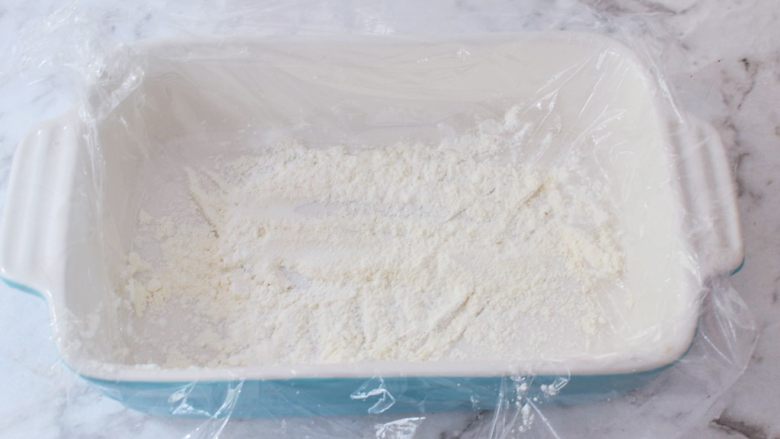 胡萝卜麻薯,容器中铺上保鲜膜,再撒上一层熟粉备用