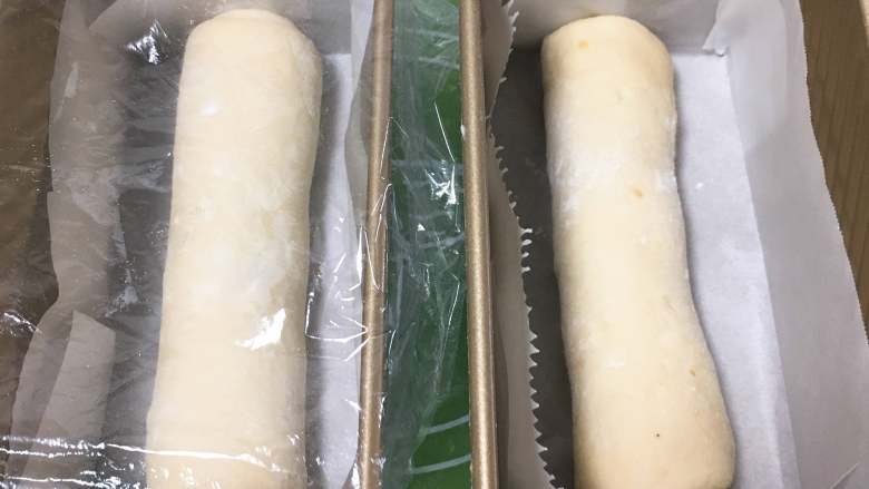 巧克力味肉松蛋糕吐司,吐司盒底部铺上烤盘纸,面团放入,盖上保鲜膜。