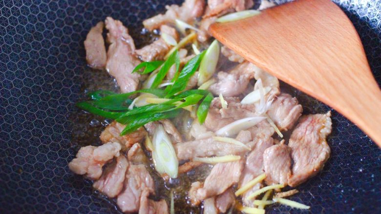 黄花菜炒肉片,大火继续翻炒片刻,加入葱姜炒出香味。