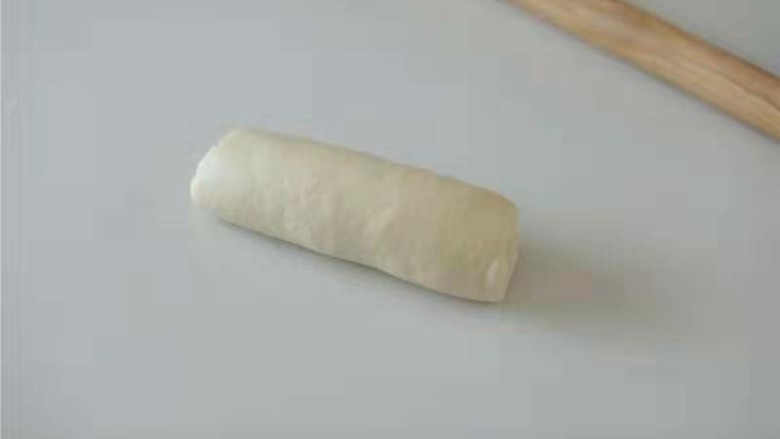 奶香红豆吐司,翻面,卷起,依次做好盖保鲜膜28度醒发20分钟左右