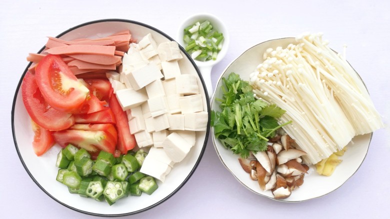 番茄菌菇豆腐汤,所有食材清洗干净,西红柿、豆腐切块,金针菇切去底部,香菇切小块,火腿切条,秋葵、香菜切断,姜切片,葱切末。