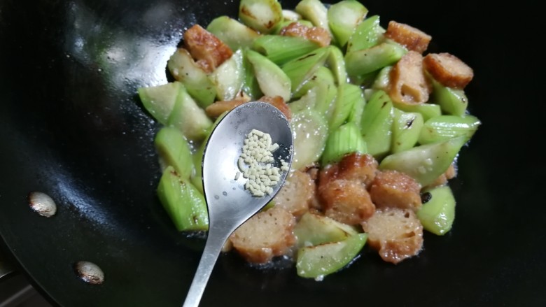 蒜香丝瓜炒油条,放入少许鸡精,撒入蒜末拌匀
