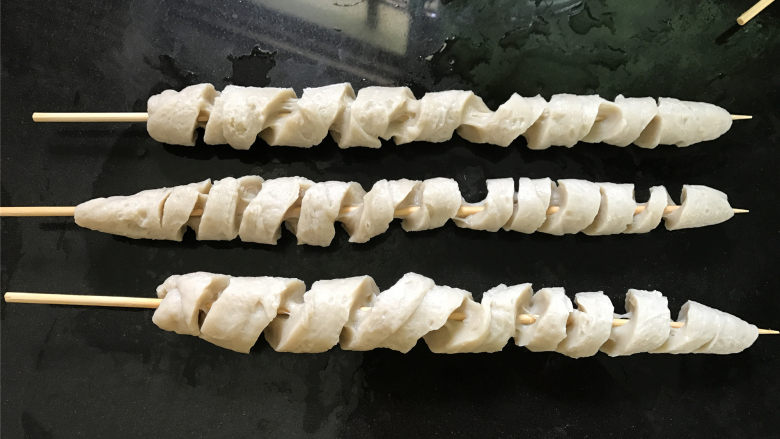 烤面筋,把煮好的面筋取出,放入准备好的冰水中,让其冷却。
把冷却好的面筋用竹签插起来,用刀滚刀切开。