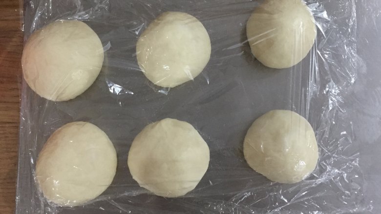 花环面包,将面团拿出排气,分割成80G每个的小面团,滚圆后盖保鲜膜松弛15分钟。
