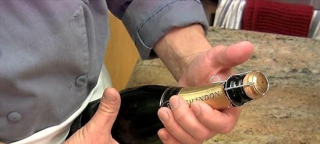 石榴气泡鸡尾酒,左手用大拇指紧紧按住木塞顶部后,右手才慢慢去拧开铁丝网上的扣子,不要让木塞弹出去