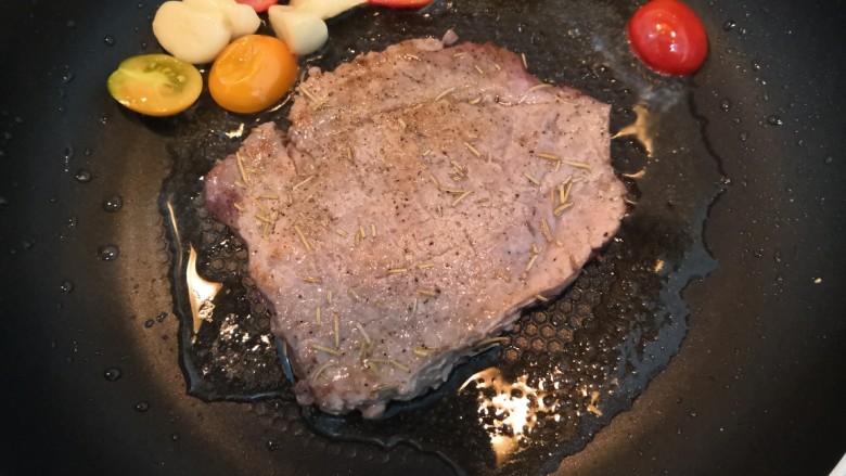 迷迭香黑胡椒牛排,牛排一面煎至变色后,翻面再煎