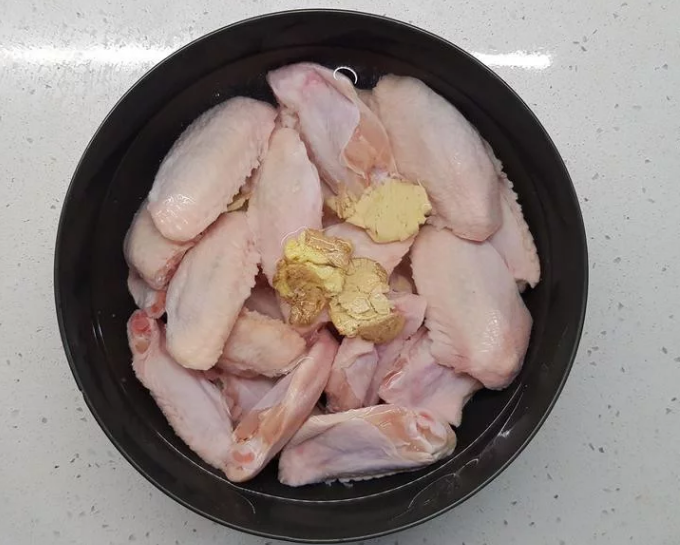 蒜香蜂蜜啤酒鸡翅,鸡翅洗净,放入冷水,加入拍碎的薑段、少许盐一起浸泡30分,去除腥味及多餘的血水。