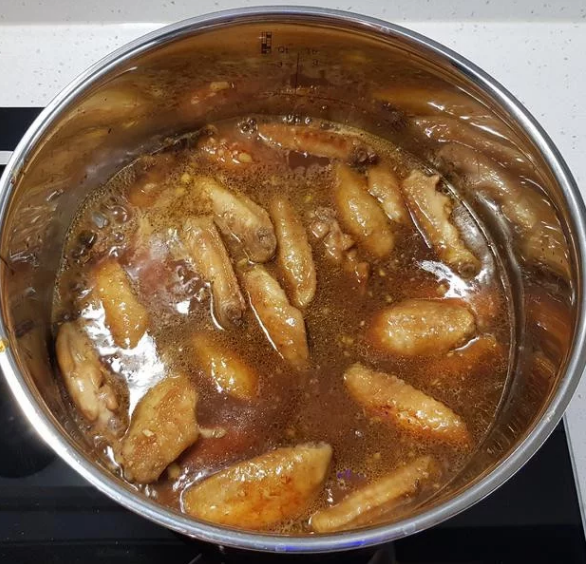 蒜香蜂蜜啤酒鸡翅,加入醃肉酱汁,煮沸后捞除表面浮末。加入煎好备用的鸡翅,盖上锅盖,以中火燜煮20分鐘。