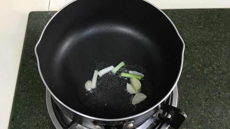 蛤蜊蒸蛋,锅中倒入食用油,小火炒香蒜片和小葱段。