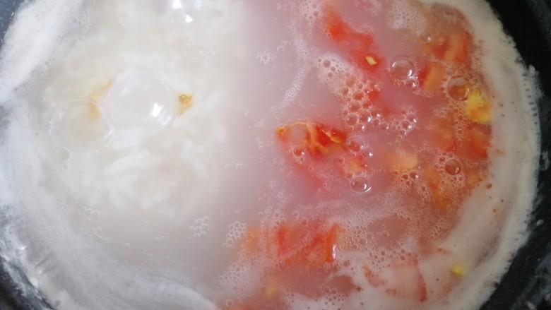 番茄丝瓜补钙粥,煮粥时间到,开锅,放入西红柿丁