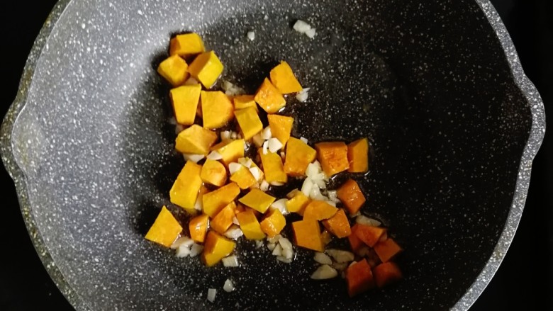 南瓜肉末炒饭,锅内倒入适量的油,倒入蒜末和南瓜翻炒