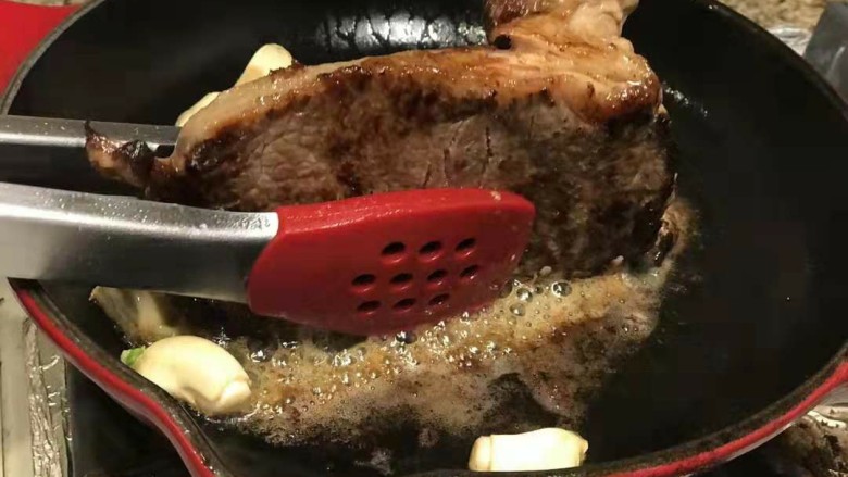 迷迭香黑胡椒牛排,随后放入蒜瓣,煎2分钟牛排竖起来也煎熟