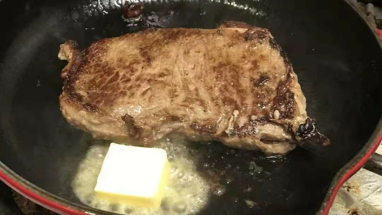 迷迭香黑胡椒牛排,等牛排表面有一点点焦的时候放入黄油,待黄油融化,将牛排二面都沾上黄油