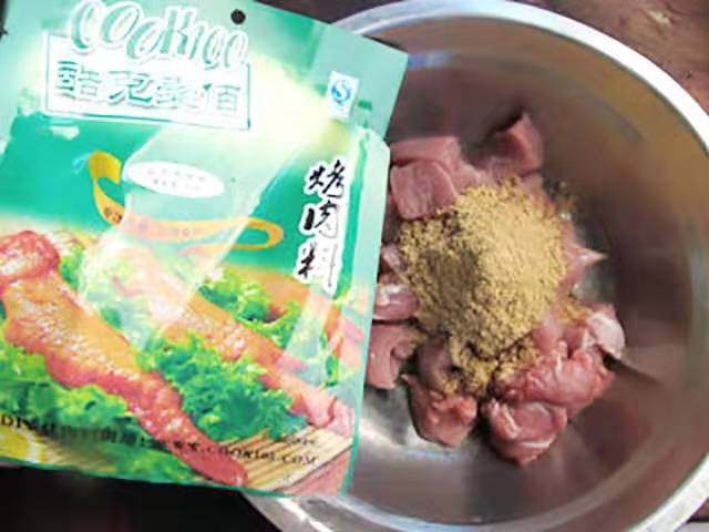 孜然羊肉串,把肉丁放入盆里,倒入25克的孜然烤肉料