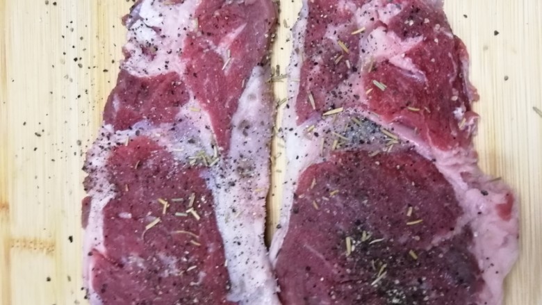 迷迭香黑胡椒牛排,肉上均匀的撒上黑胡椒和盐,还有迷迭香