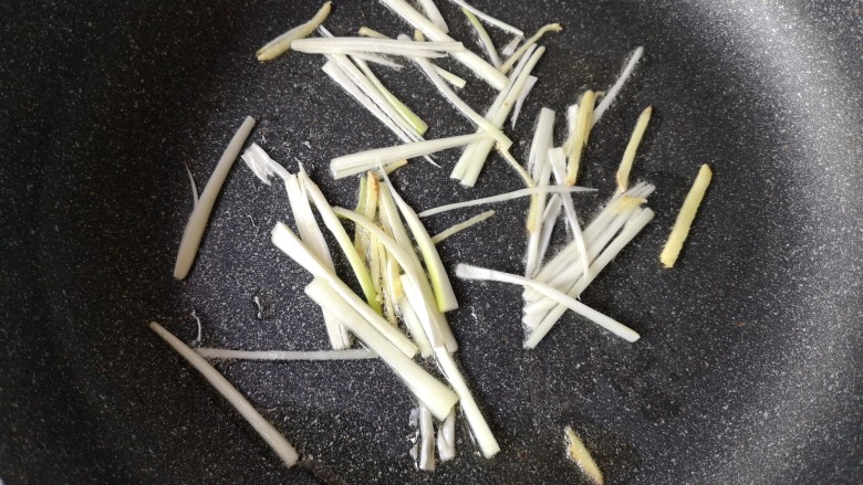 官烧目鱼,另起一锅,倒入少量油,下另一部分葱姜丝爆出香味。
