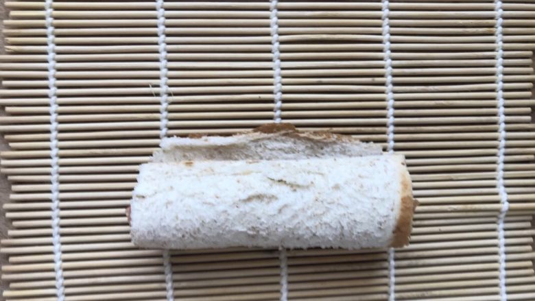 早餐吃什么—火腿吐司卷,把煎好的火腿放进去,把吐司卷起来,放到卷帘上