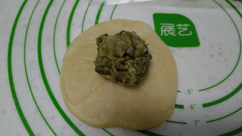 绿豆酥饼,取一个用拇指在中间压一下,两头收起,擀成薄片,放入绿豆沙。