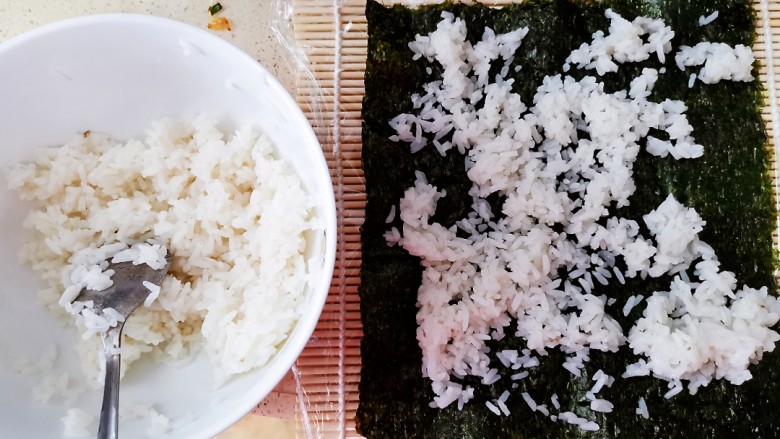 肉松寿司,米饭(家里没有东北米了,但是用东北米会更好吃)煮熟后取小碗半碗(两卷寿司的量),倒入适量<a style='color:red;display:inline-block;' href='/shicai/ 4734'>寿司醋</a>,小半瓶就行,因为倒太多会有点酸,拌匀,然后待它放凉,寿司帘上卷一层保鲜膜,放上一张海苔,在海苔上铺一层刚才拌好的米饭(亲测,米饭一定不要铺多了,不然做出来的寿司卷起来一大卷不好吃也不好卷),米饭看图片上的量就可以了,稍微铺均匀一点