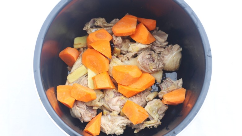 山药香菇玉米土鸡汤,鸡肉连同姜片一起放入锅中,加上胡萝卜。