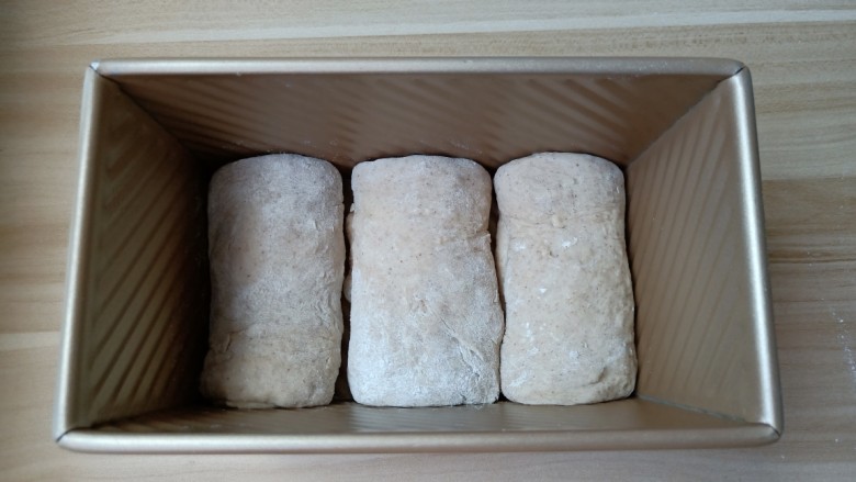 黑麦全麦吐司,由上至下卷起来,卷的时候注意卷紧,不要留下缝隙。卷好的面团放入土司盒里。