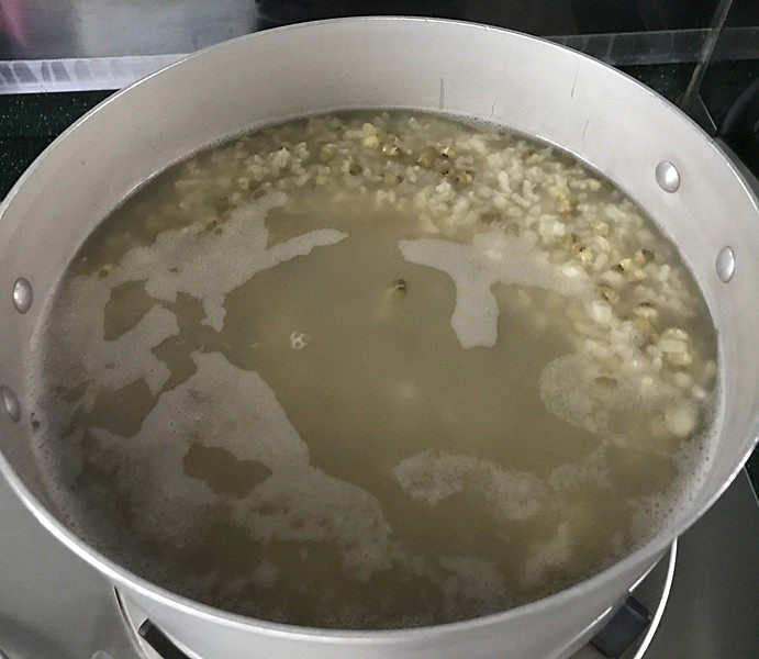 绿豆粥,此时锅中的水变少了,大米开花了,绿豆也逐渐涨发开了,有没有