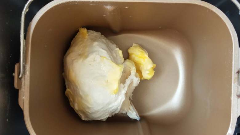 鲜奶油土司,3、揉成团后加入软化的黄油继续揉。