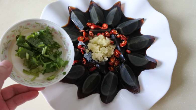 凉拌皮蛋,把小米椒、香菜、蒜泥撒在上面。吃的时候拌匀即可