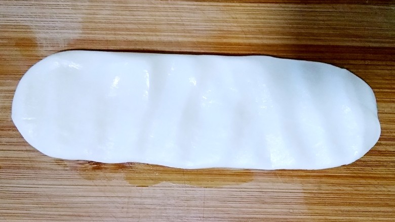 陕西油泼面,取一条面,在案板上按扁。