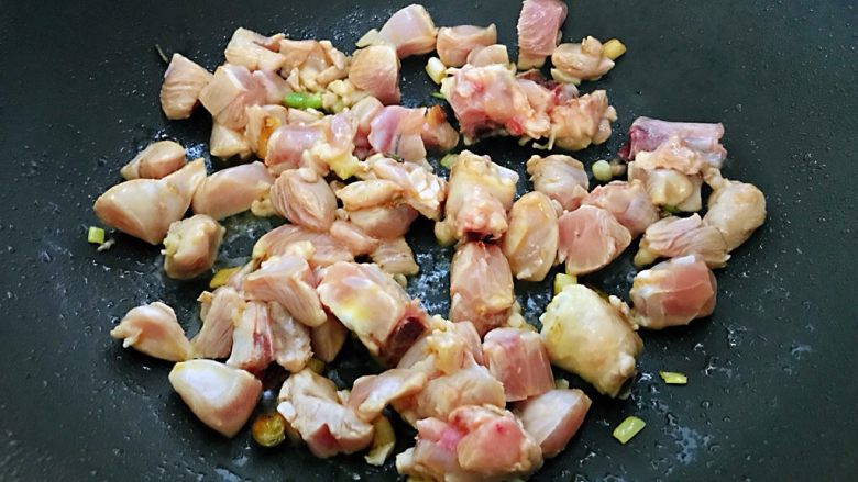鸡腿焖米饭,锅烧热,加入少量油,放入葱爆炒出香味,加入腌制好的鸡腿炒至肉变色。