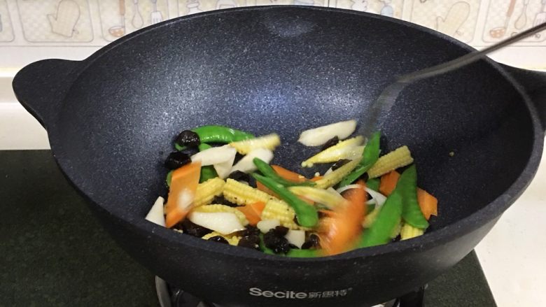 玉米笋炒时蔬,接着先倒入胡萝卜片翻炒变色,继续倒入黑木耳、山药、荷兰豆和玉米笋翻炒几分钟至熟。