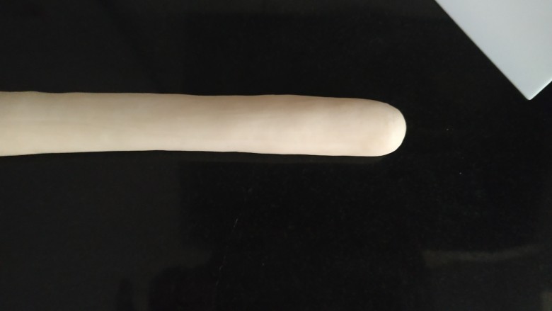 咸蛋黄糯米烧麦,饺子粉和饮用水大概2:1左右比例,具体根据使用面粉的吸水率增减,在蒸糯米时候用厨师机揉好,揉完的面团取小团,放在操作台上,团圆静置松弛5-10分钟,用双手挫成长条形的剂子;