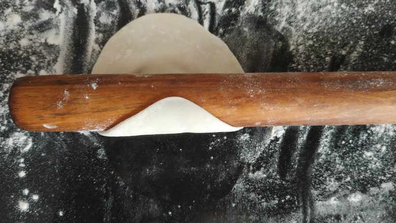 咸蛋黄糯米烧麦,用擀面杖从圆的边缘往中间擀,用力均匀,擀一下,用另一只手拿饺子皮转一下,把一圈都擀到,这样就是饺子皮,中间厚边缘薄的状态;