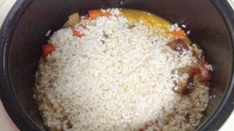 新疆特色手抓饭,倒入泡好的大米,铺平