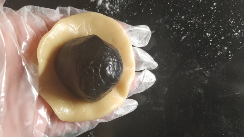 广式月饼~网红大螃蟹咸蛋黄月饼,取一份月饼皮面团用手慢慢按扁成一个饼皮,放入一份馅料;