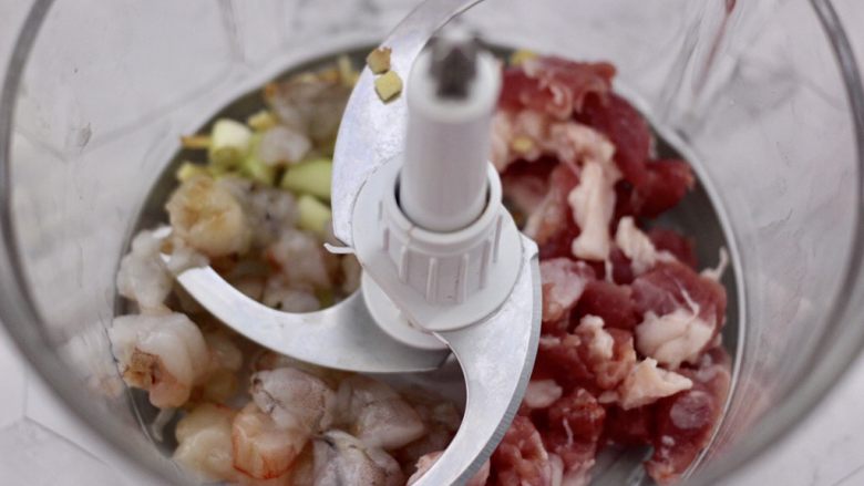 虾仁肉靡酿苦瓜,把切块的猪肉和海虾放入绞肉机里,加入切碎的葱姜。