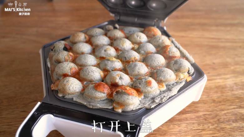 香气扑鼻的【黑芝麻芝士鸡蛋仔】,再次翻转打开上盖,将鸡蛋仔卷起取出