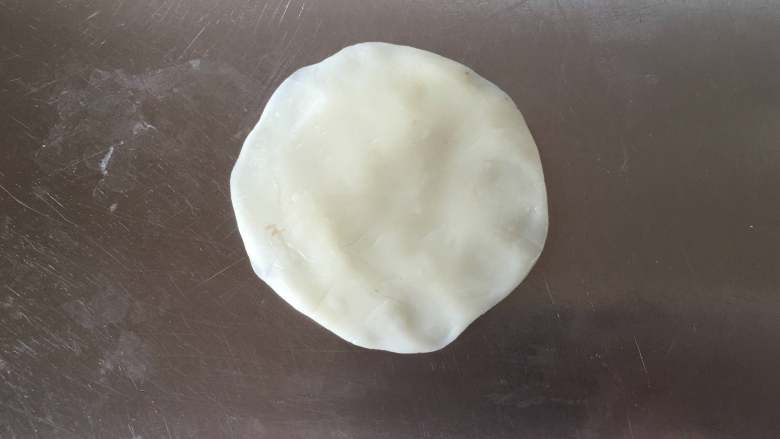 莲蓉蜜豆冰皮月饼,取一个冰皮将其压扁,边缘稍微薄一些。